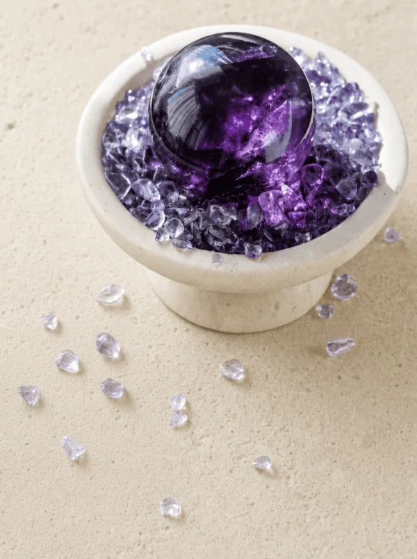 Stone Blessings amethyst sphere centerpiece styled on a tabletop with loose chevron amethyst chips scattered around the stone vessel