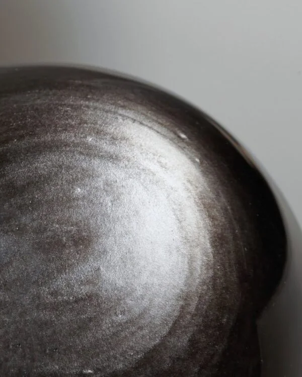 Stone Blessings close up of a natural volcanic obsidian sphere showing the polished black stone surface and subtle banding