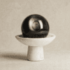 Stone Blessings natural volcanic obsidian sphere on a hand carved travertine pedestal bowl front view