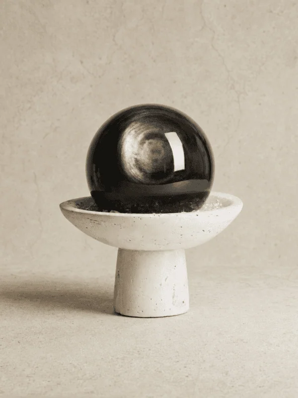 Stone Blessings natural volcanic obsidian sphere on a hand carved travertine pedestal bowl front view