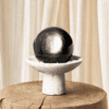 Stone Blessings obsidian sphere centerpiece styled on a raw wood log with soft cream curtains in a quiet natural setting