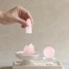Stone Blessings rose quartz centerpiece shown with a hand placing a rose quartz tower into the travertine pedestal bowl